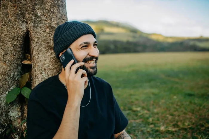 A man on a phone call outdoors, smiling.